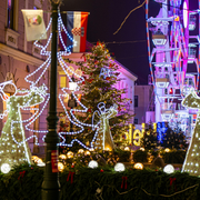 Festive street scene with Christmas lights, decorated trees, and a Ferris wheel at night