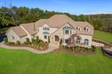 Large beige two-story suburban house with a landscaped front yard and curved walkway