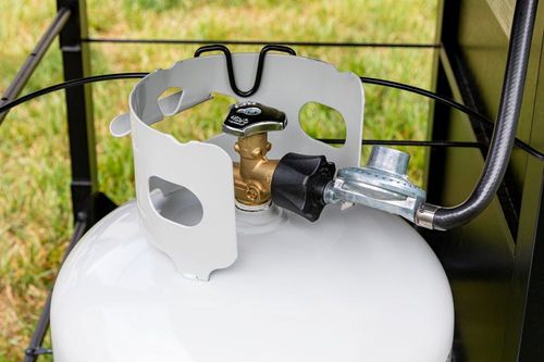 White propane tank with regulator and hose attached inside a metal cage outdoors