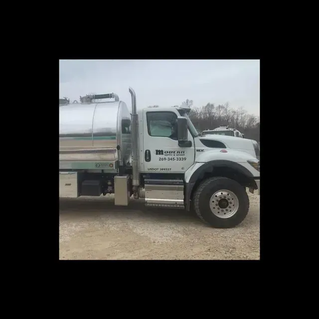 White tanker truck with chrome tank, parked on a dirt lot.