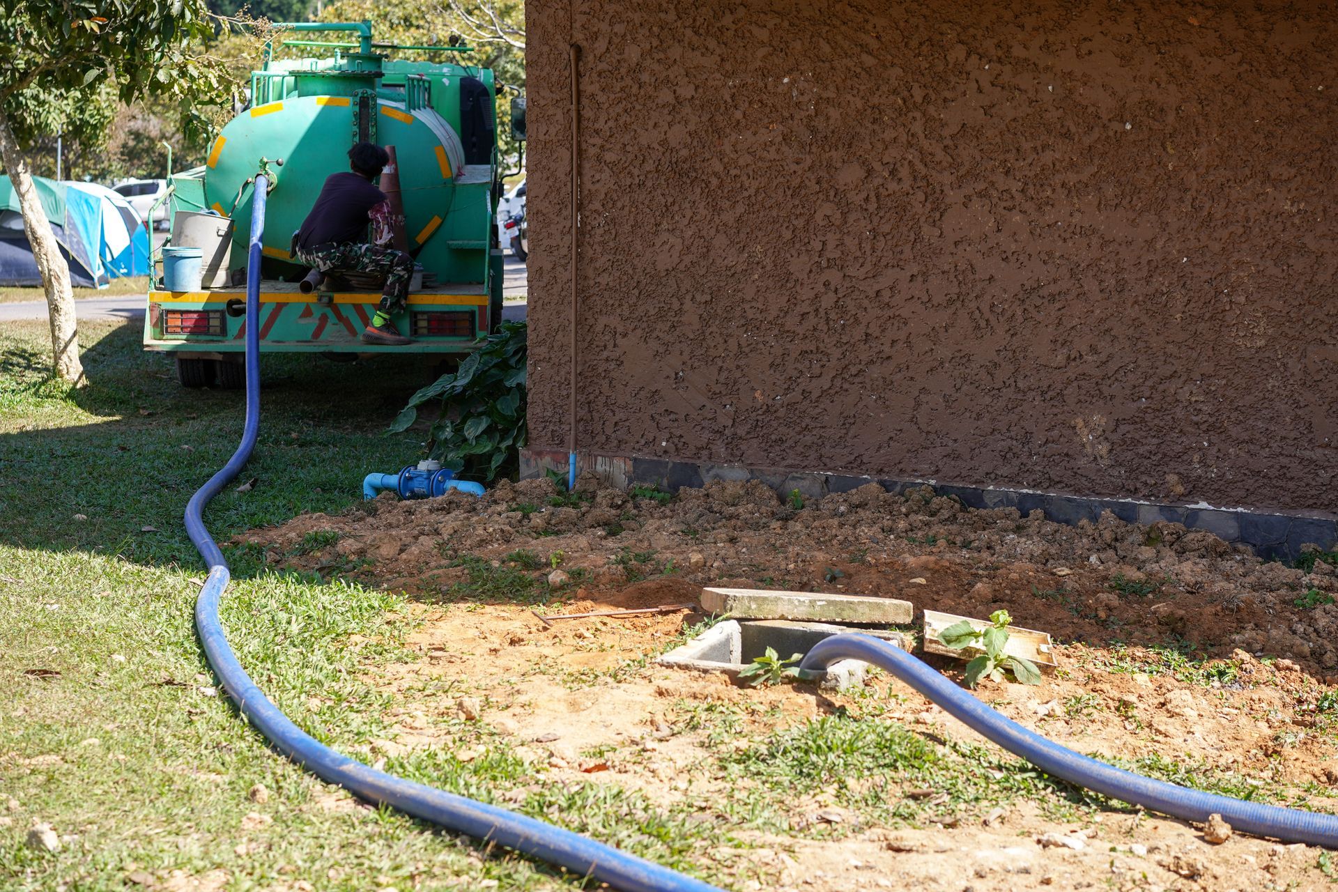 Septic pump truck with hose connected to an open septic tank access lid.