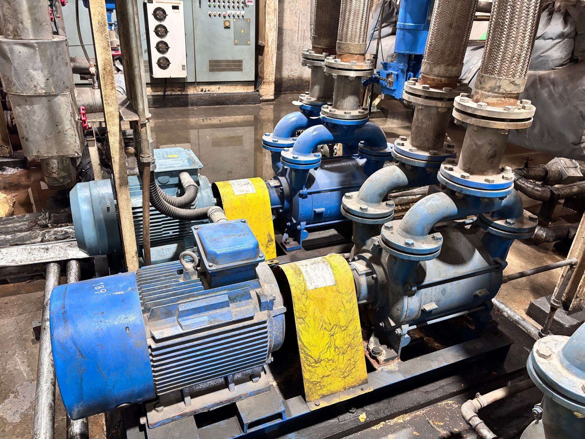 A pair of electric blue industrial centrifugal pumps and motors with associated heavy piping.