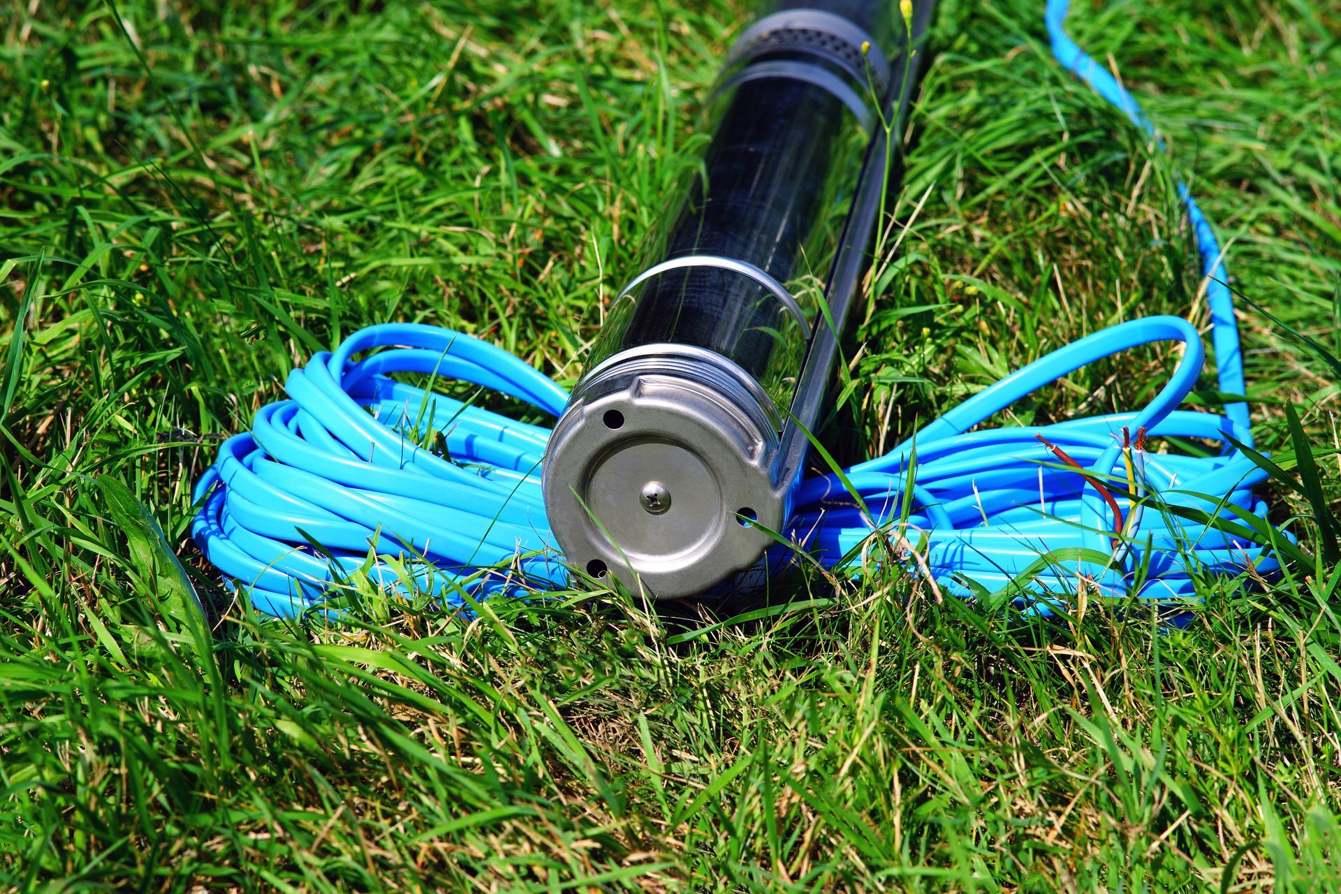 Electric well pump with blue cable on the ground.