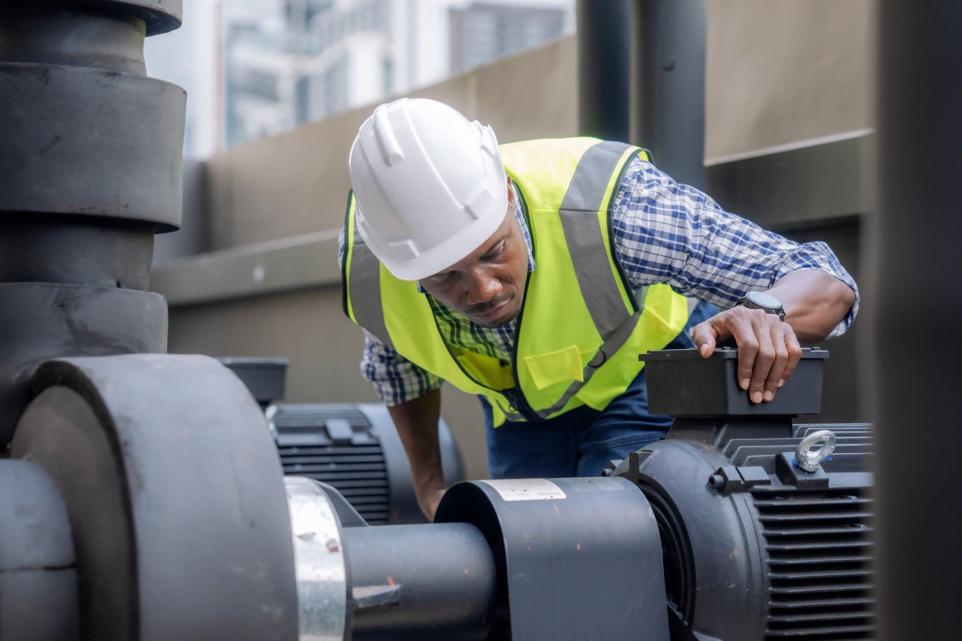 An engineer in safety gear inspects a large centrifugal pump at a facility.