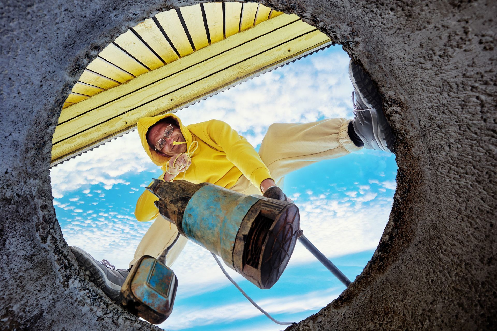 A man immerses a waste pump into wastewater through a hole in a concrete well ring. A man immerses a waste pump into wastewater through a hole in a concrete well ring.