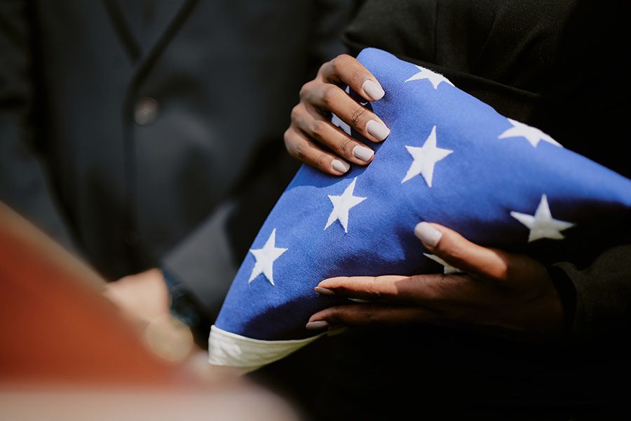 A man in a military uniform is holding an american flag in his hands.