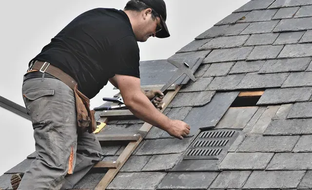 A man is working on the roof of a house.