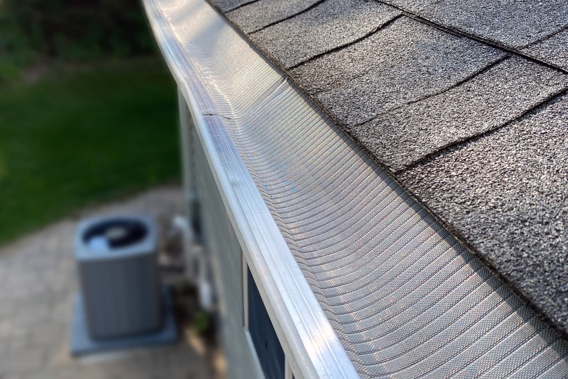 A close up of a gutter on a roof next to an air conditioner.