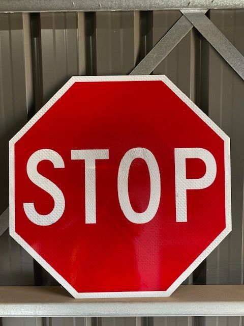 A stop sign is hanging on a metal wall