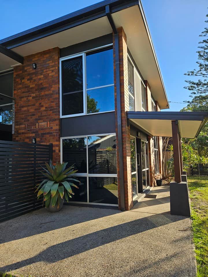A House With a Lot of Windows and Bushes in Front of It — PJ Tinting In Port Macquarie, NSW
