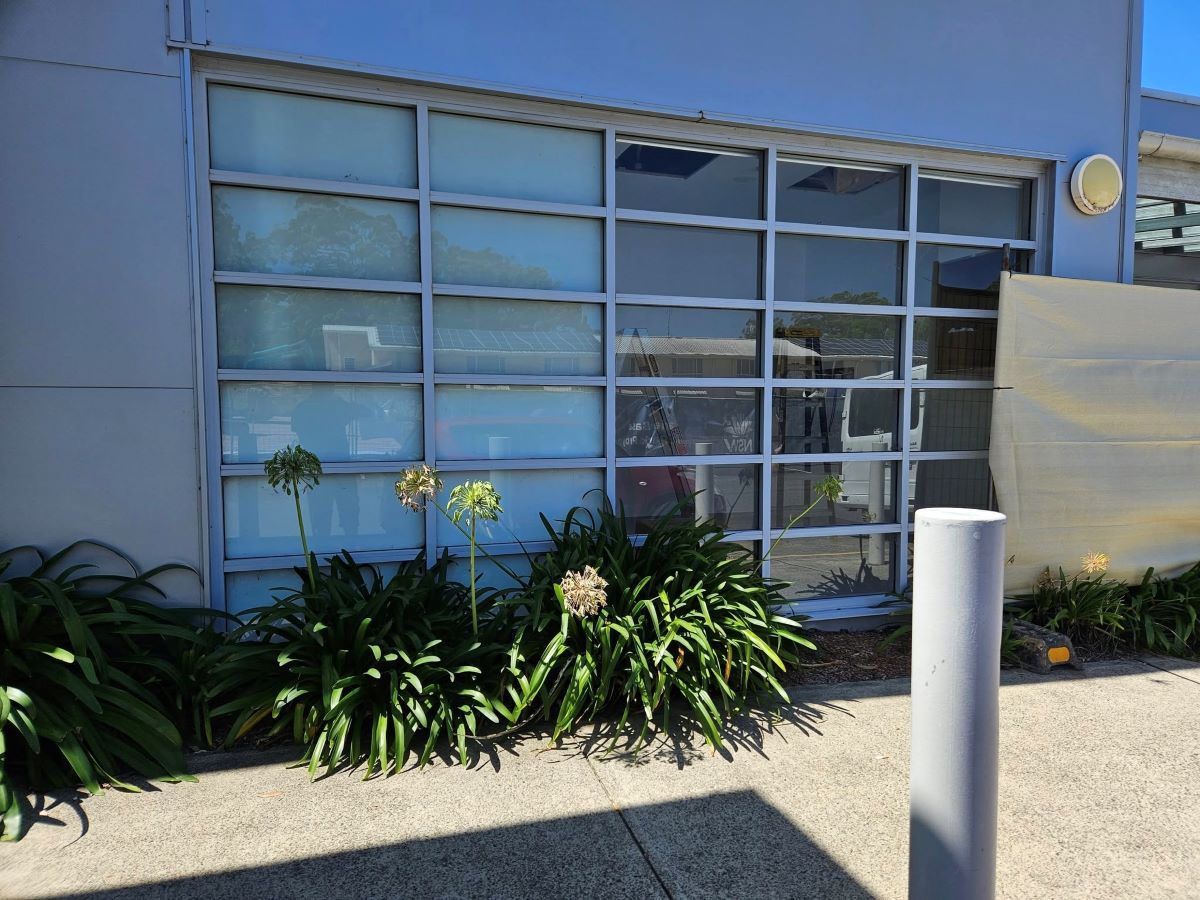 A Building With a Lot of Windows and Plants in Front of It — PJ Tinting In Bonny Hills, NSW