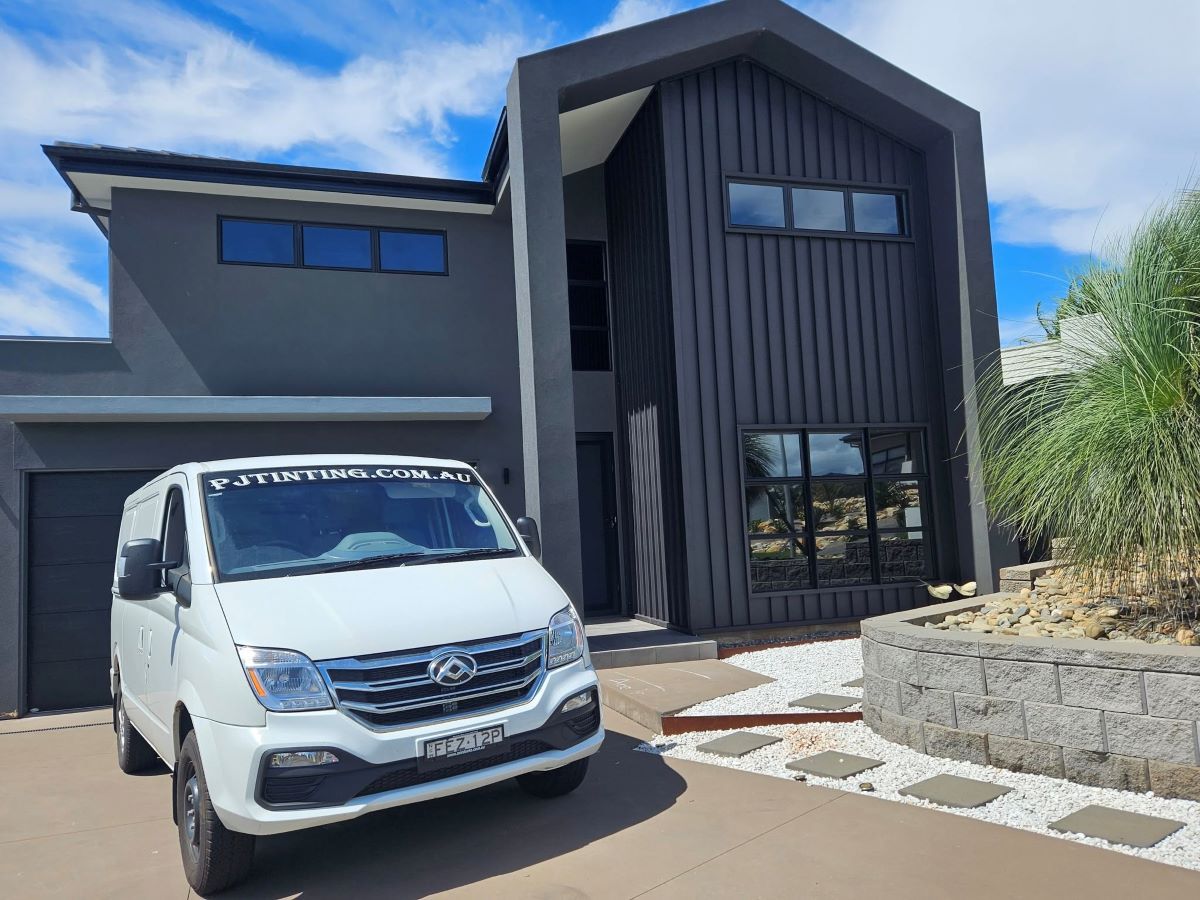 A White Van is Parked in Front of a Large House — PJ Tinting In Port Macquarie, NSW
