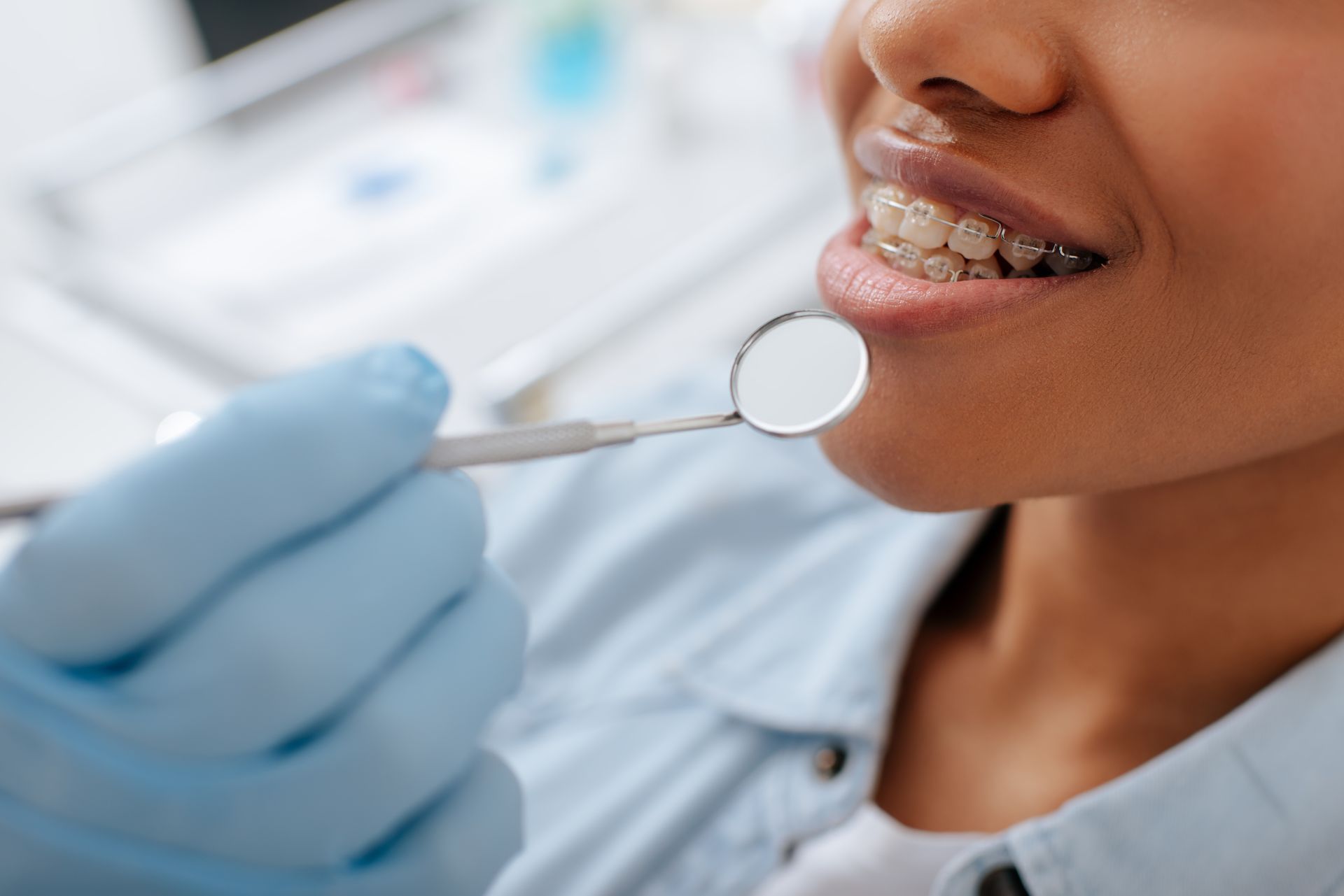 orthodontist holding a dental mirror near a smiling patient wearing braces