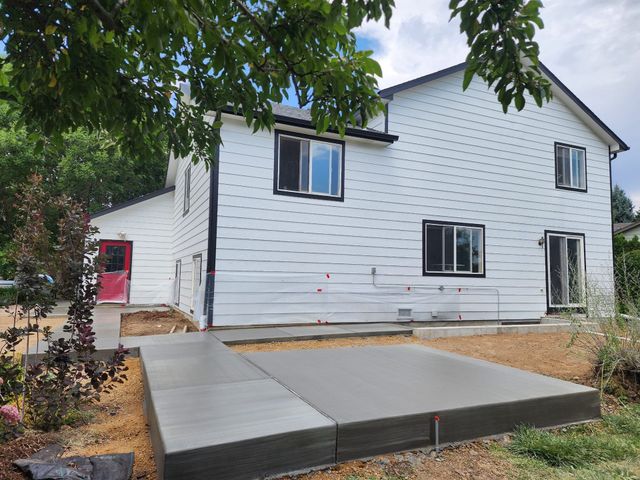New white house with black-trim windows and a concrete patio in the foreground