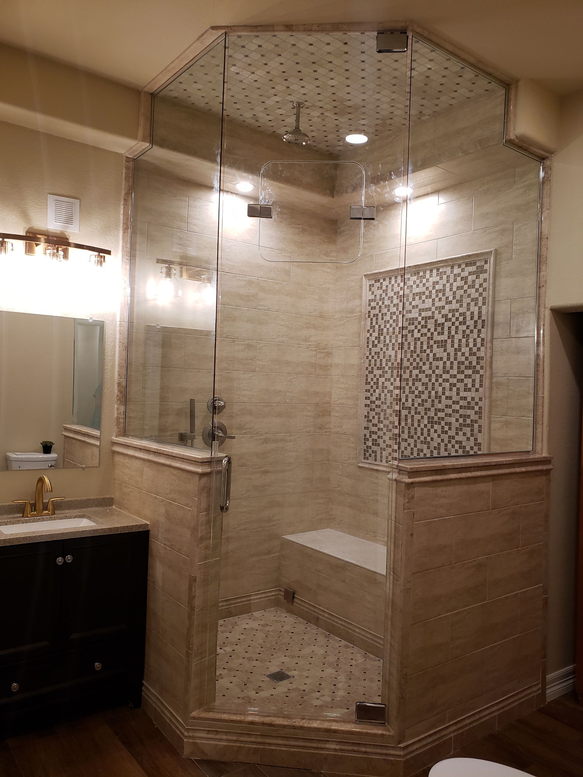 Bathroom with glass-enclosed tiled shower, vanity sink, and beige walls and trim
