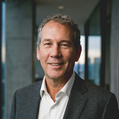 Portrait of a smiling man in a dark blazer and white shirt in a modern office hallway