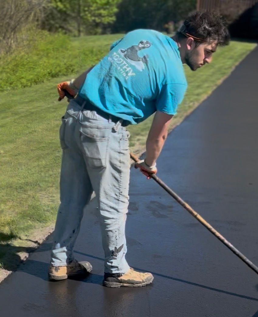 Worker spreading fresh blacktop on a paved path outdoors