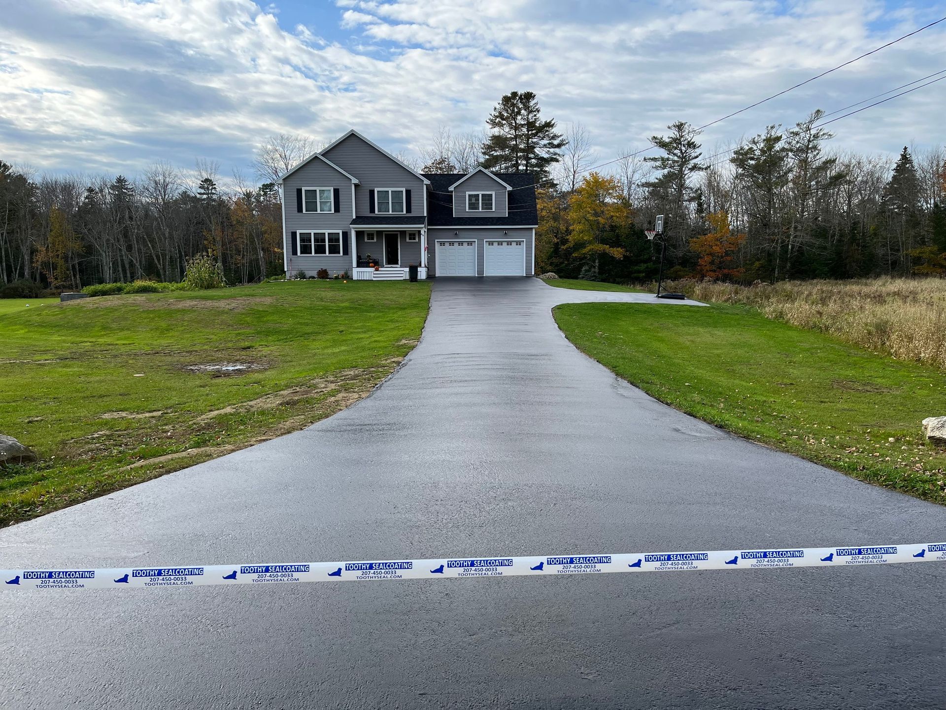 Two-story house with a long driveway, seen from behind police tape in a rural neighborhood
