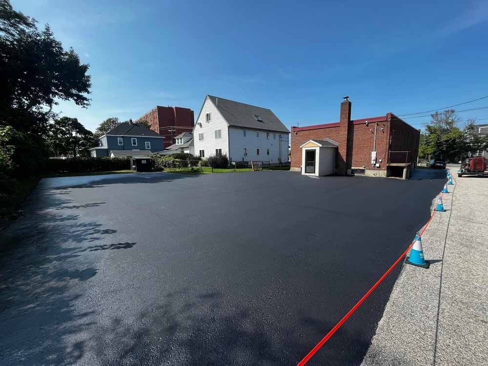 Empty paved lot beside white and red buildings under a clear blue sky