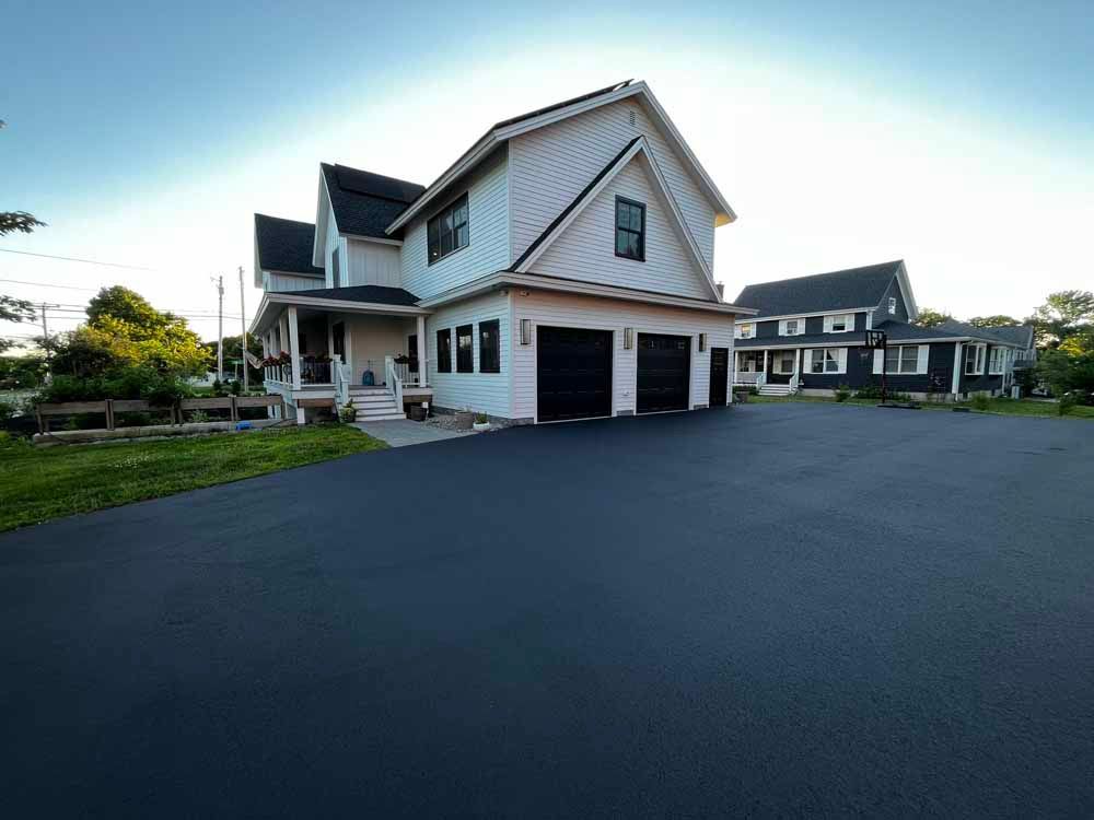 Large white house with a double garage and dark asphalt driveway on a suburban street