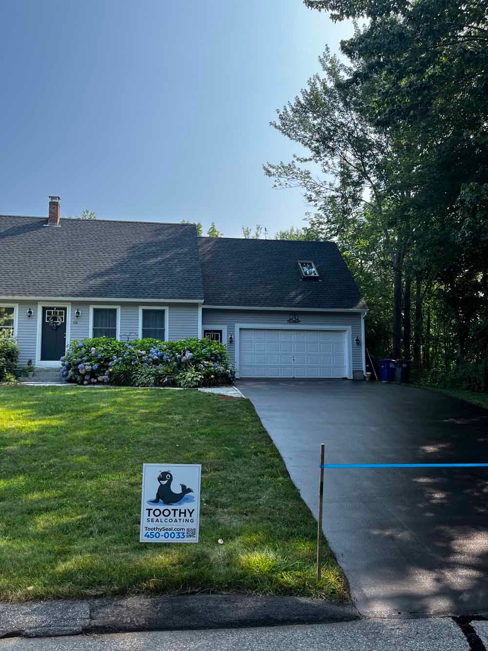 Suburban house with driveway and lawn sign reading “Trophy Homes” under a clear blue sky