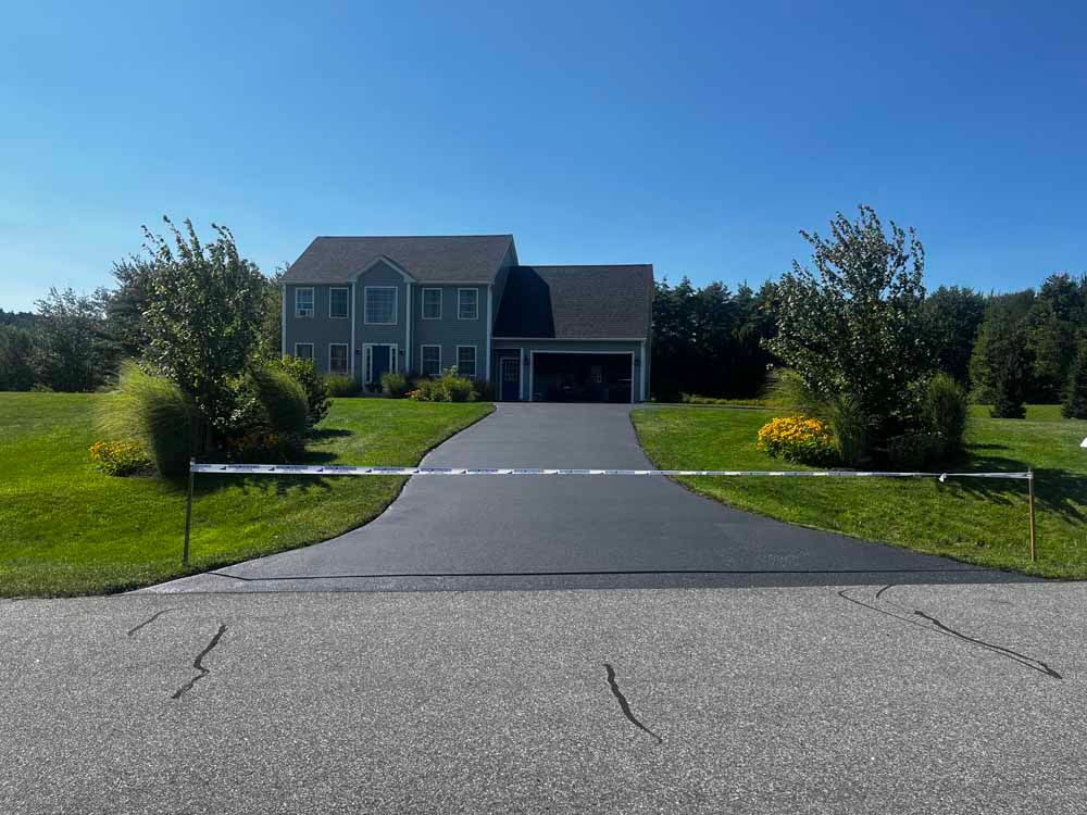 Suburban house with a long driveway, green lawn, and a clear blue sky