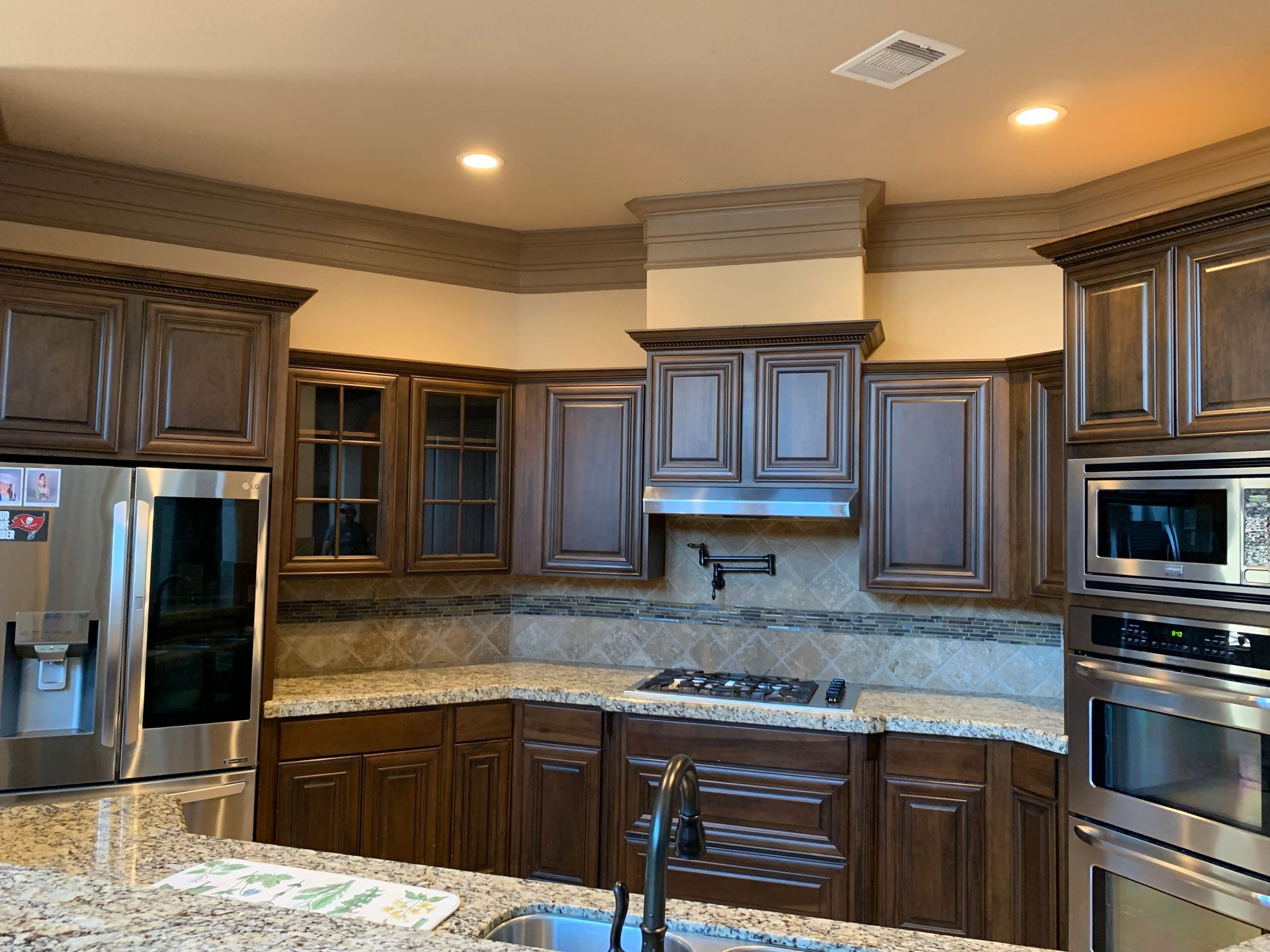 Modern kitchen with dark wood cabinets, stainless steel appliances, and granite countertops