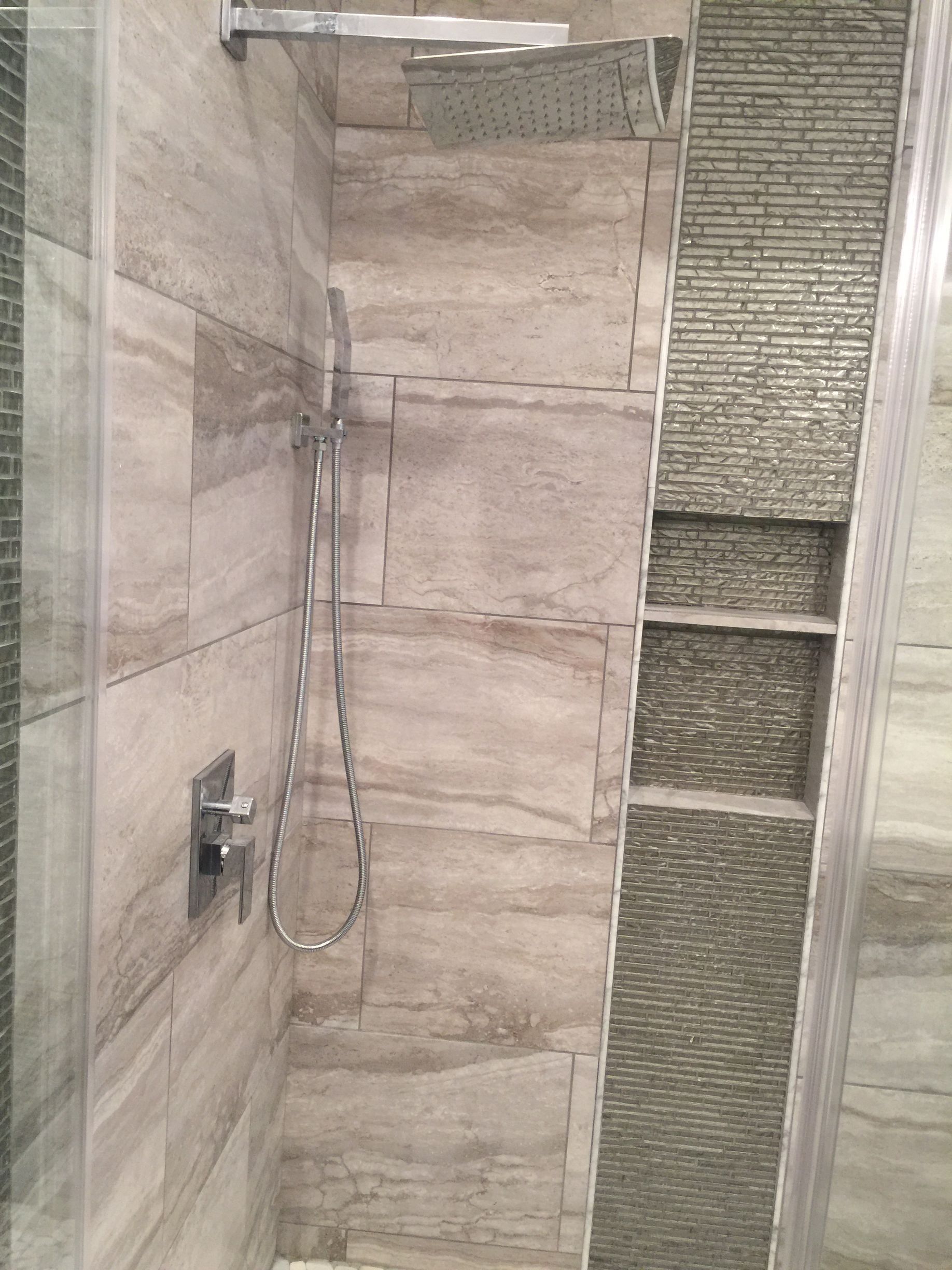 Modern shower with rainfall head, handheld sprayer, and tiled walls.