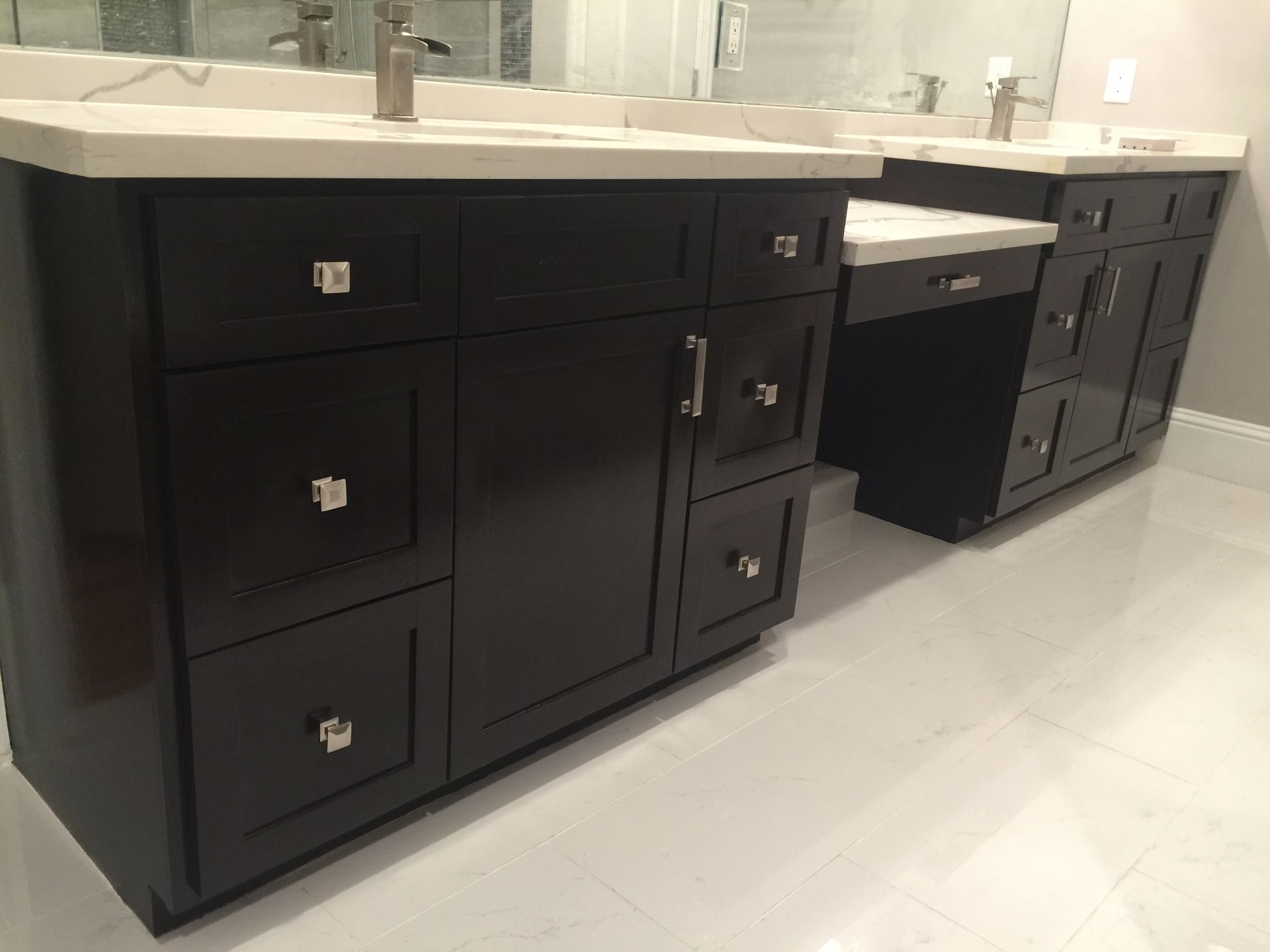 Black bathroom vanity cabinets with white countertop and sinks in a modern restroom