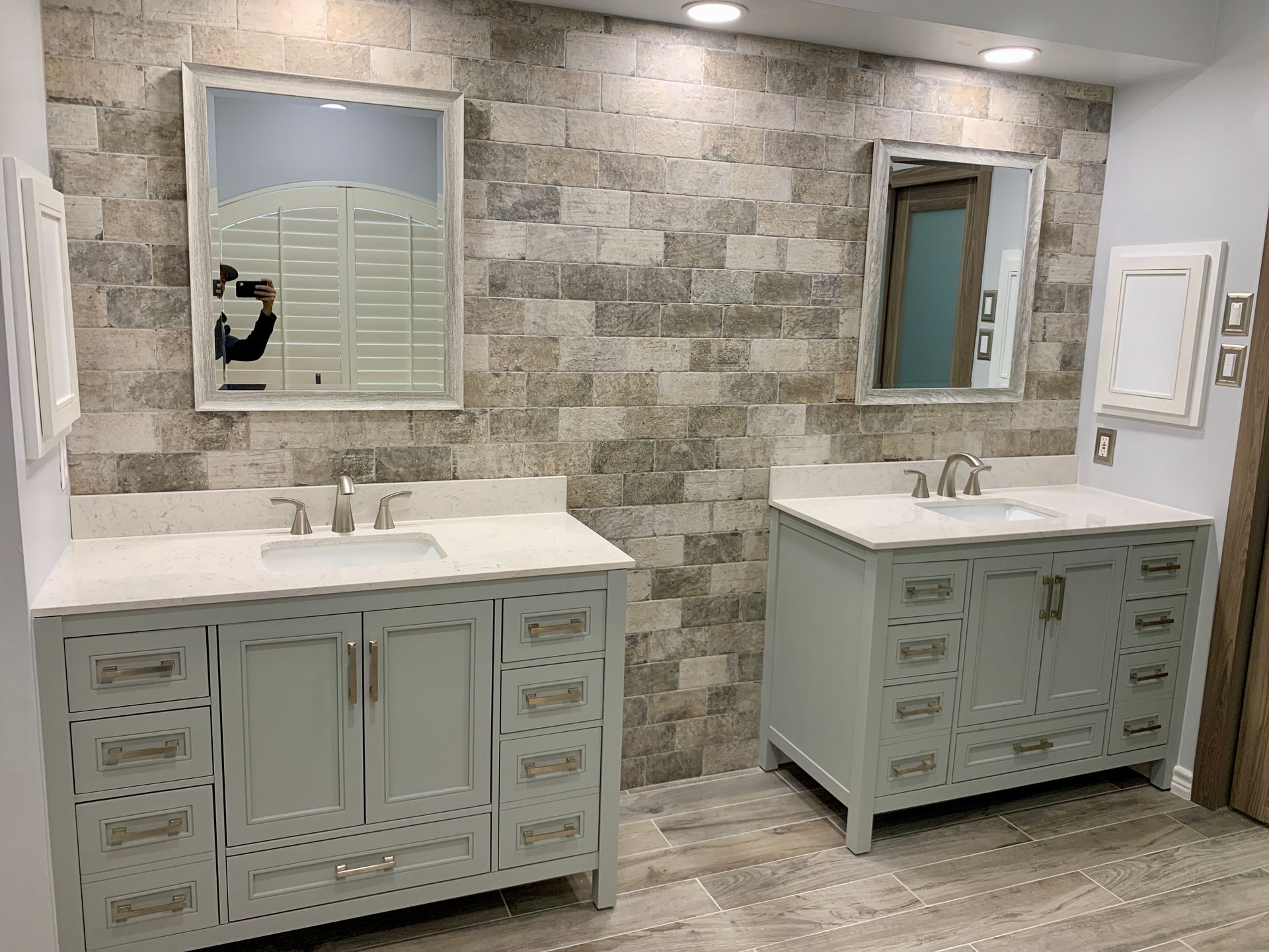 Modern bathroom with two white vanities, mirrors, and stone-pattern tile walls