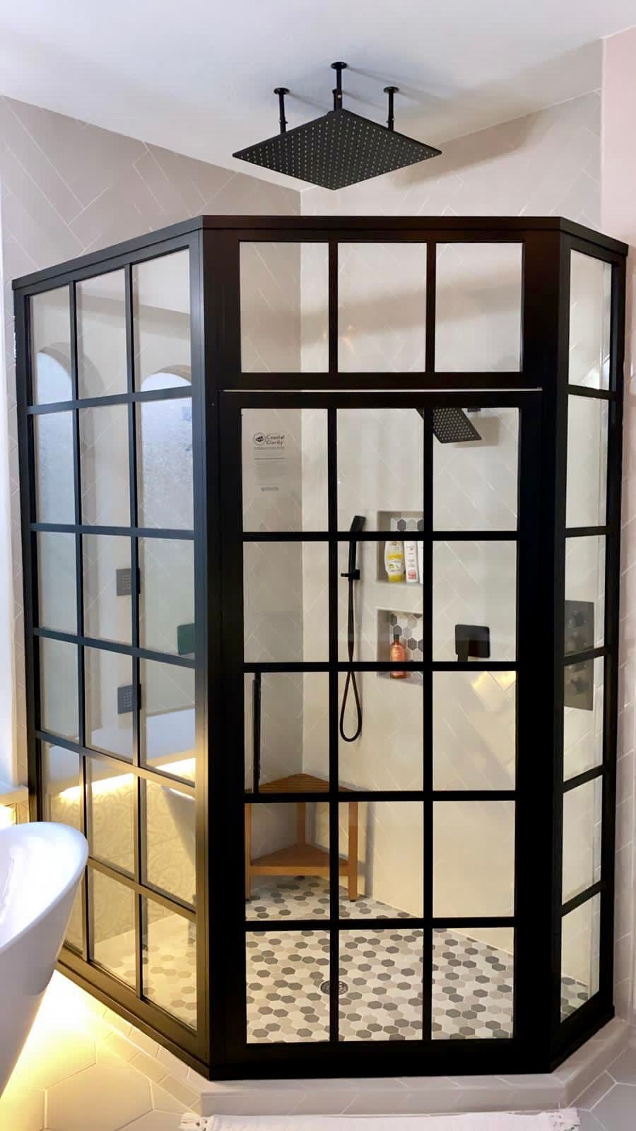 Black-framed glass shower enclosure in a modern bathroom with white tile and black accents