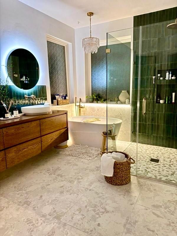 Modern bathroom with freestanding tub, glass shower, wood vanity, and round backlit mirror
