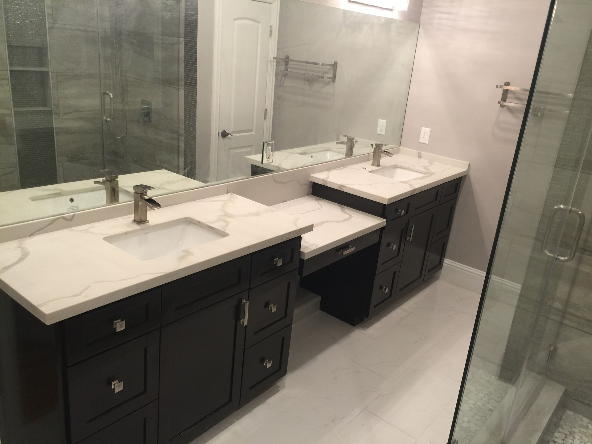 Modern bathroom with double vanity, large mirror, and glass shower doors