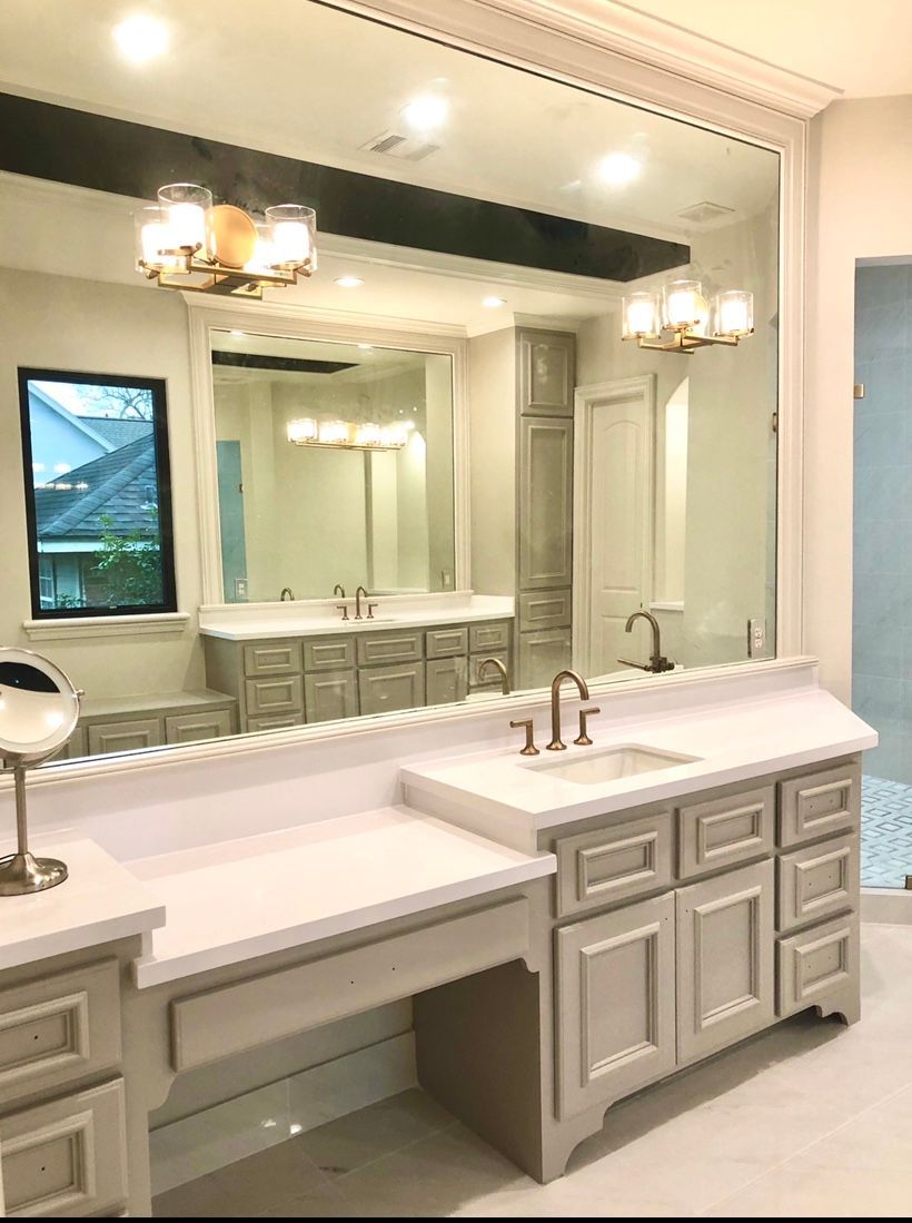 Bright bathroom vanity with double sinks, large mirror, and wall sconces in a light gray and white interior