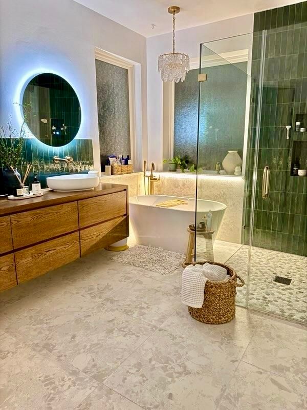 Luxurious bathroom with freestanding tub, wood vanity, round mirror, glass shower, and soft lighting