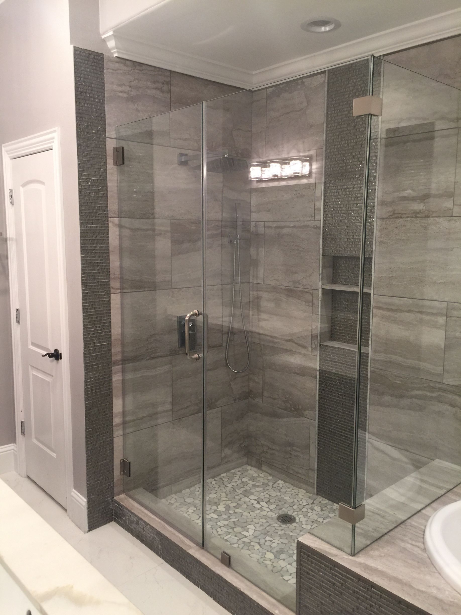 Modern bathroom with glass-enclosed tiled shower and adjacent sink in a gray interior