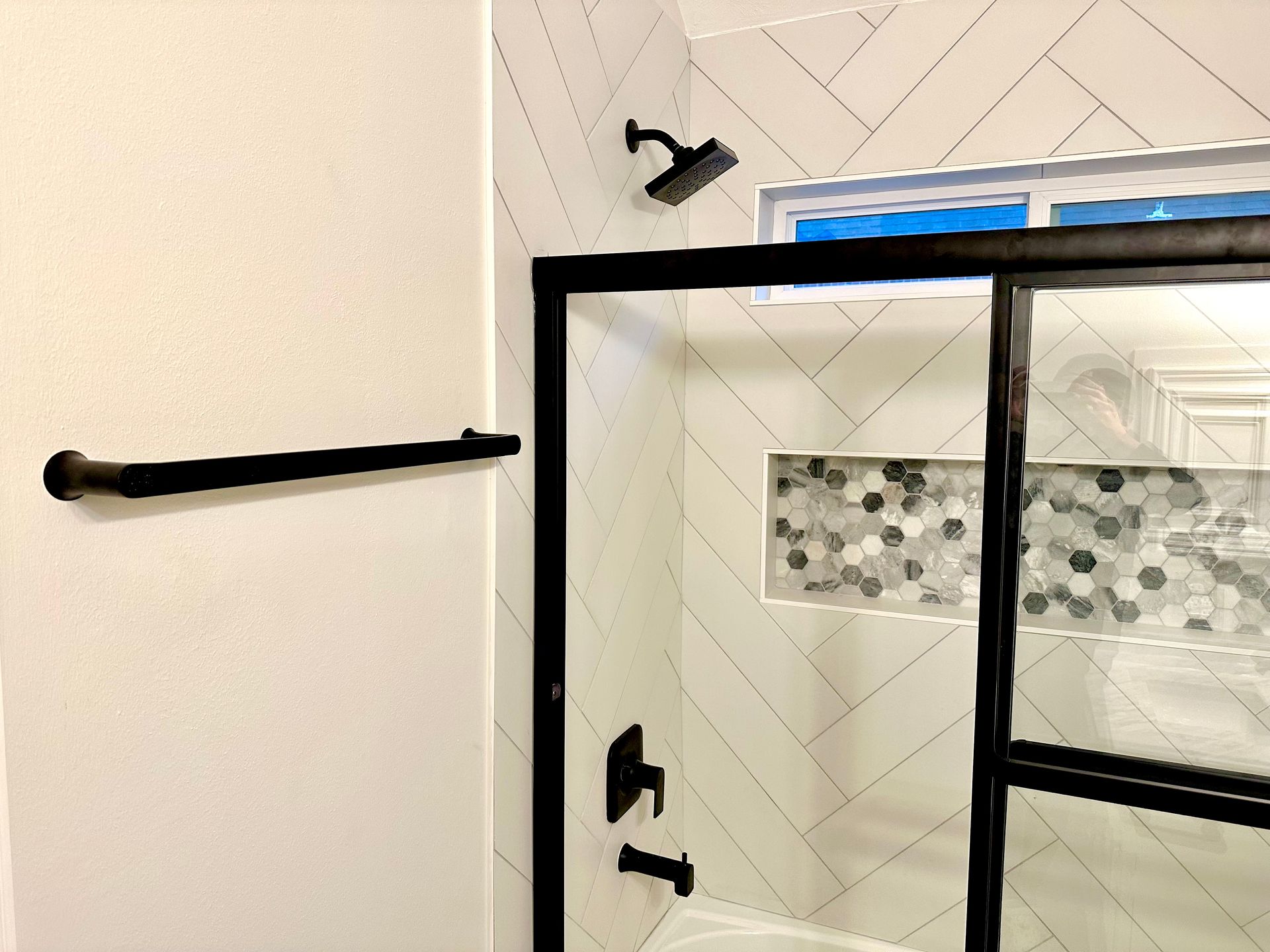 Bathroom shower with black-framed glass door, towel bar, and tiled walls