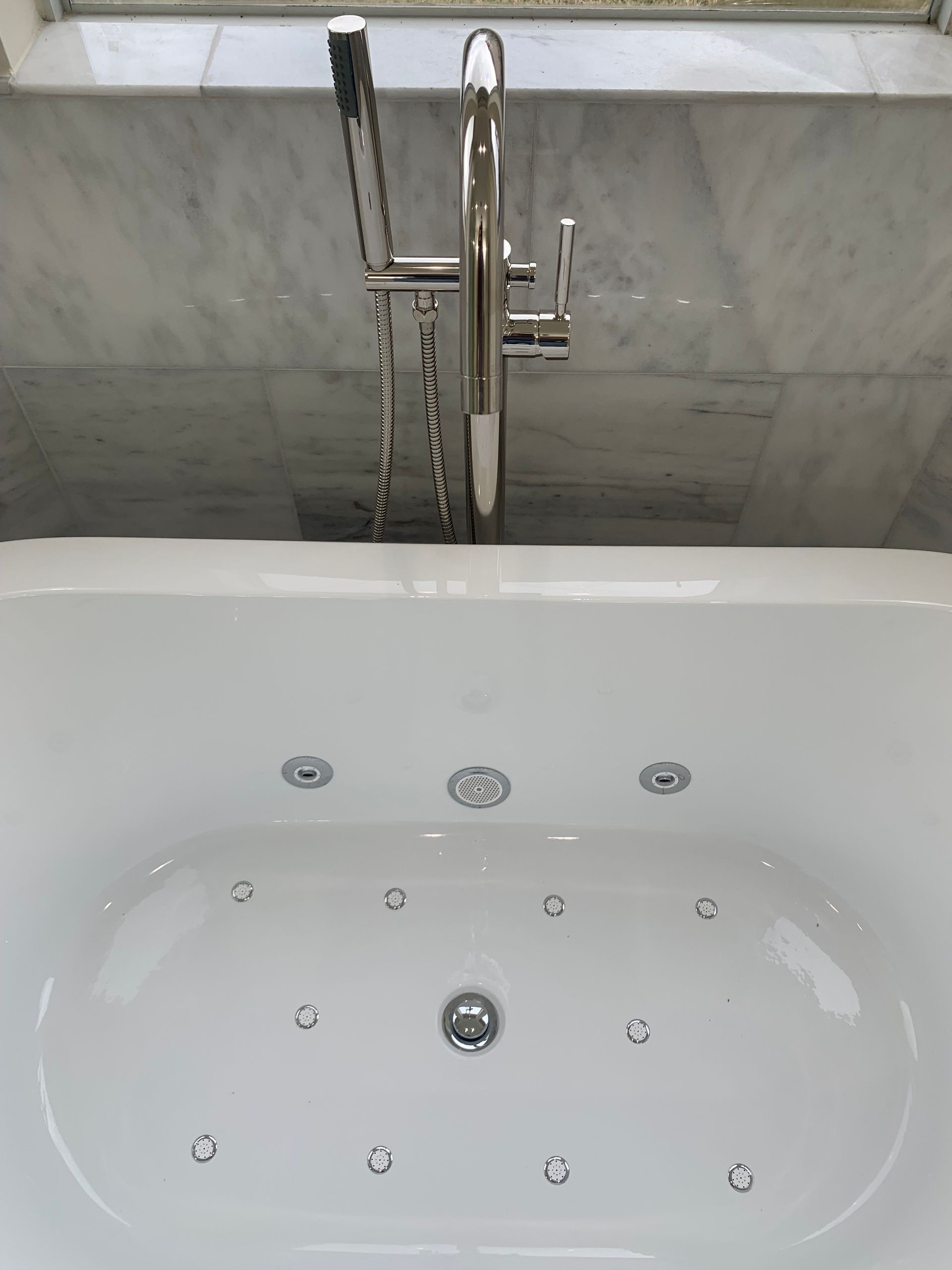 White bathtub with chrome fixtures and a tiled wall behind it.