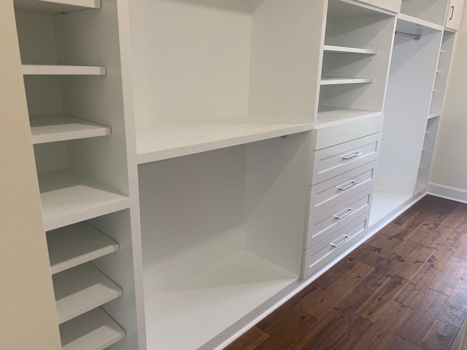 White walk-in closet with built-in shelves, drawers, hanging space, and wood flooring
