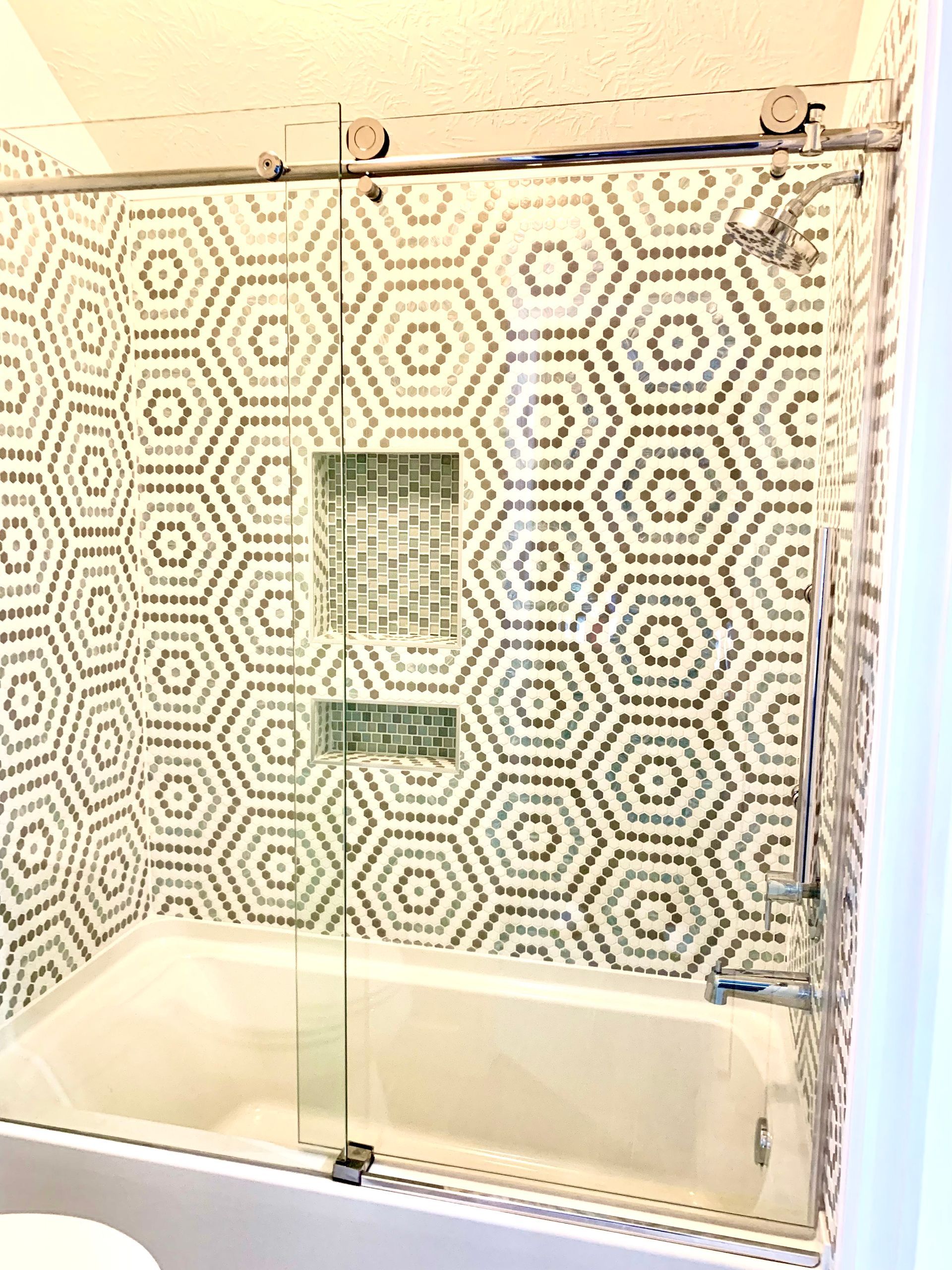 Patterned bathroom shower with clear glass panel and bathtub underneath