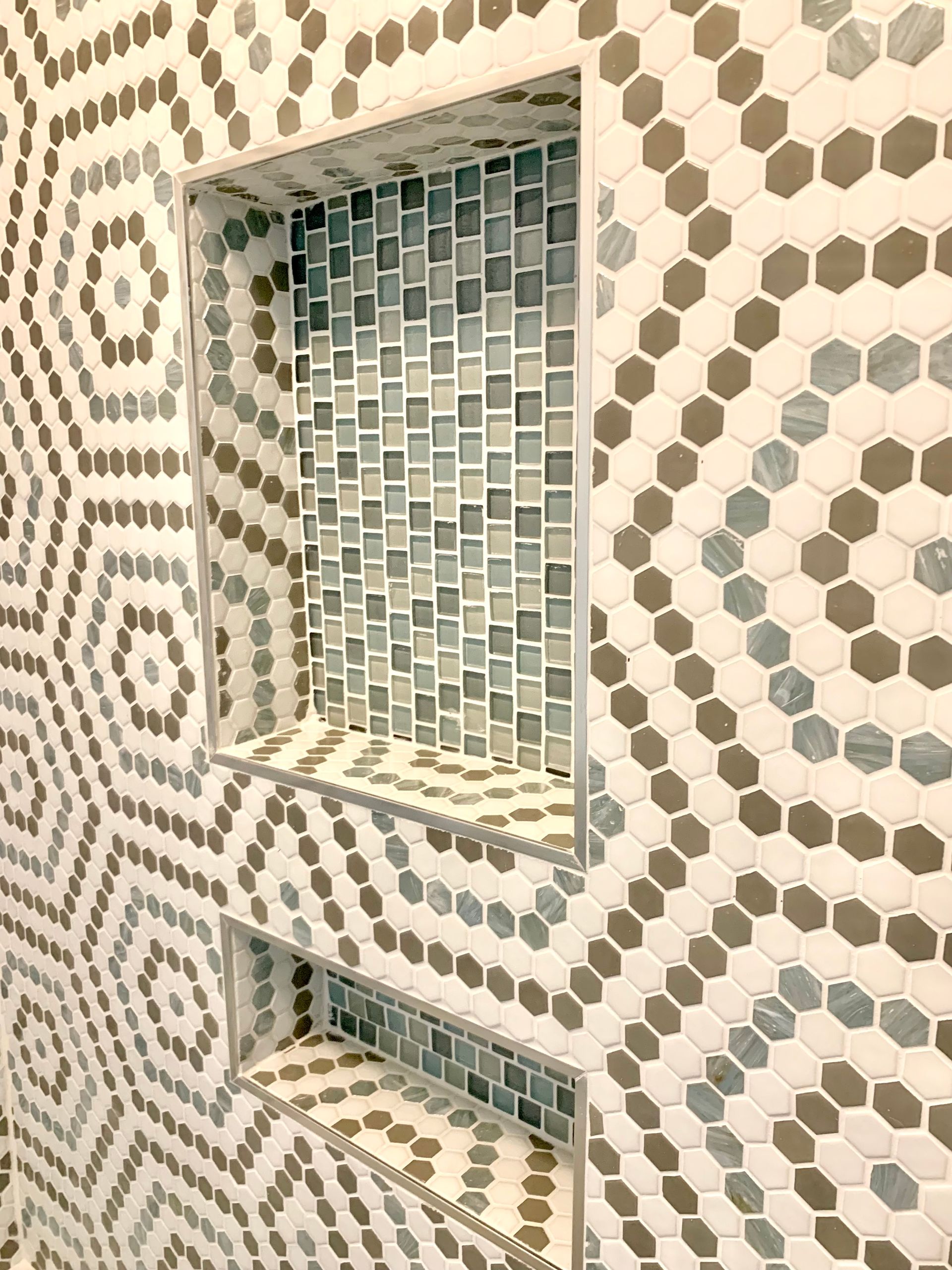 Mosaic-tiled wall with a small rectangular window and vent opening.