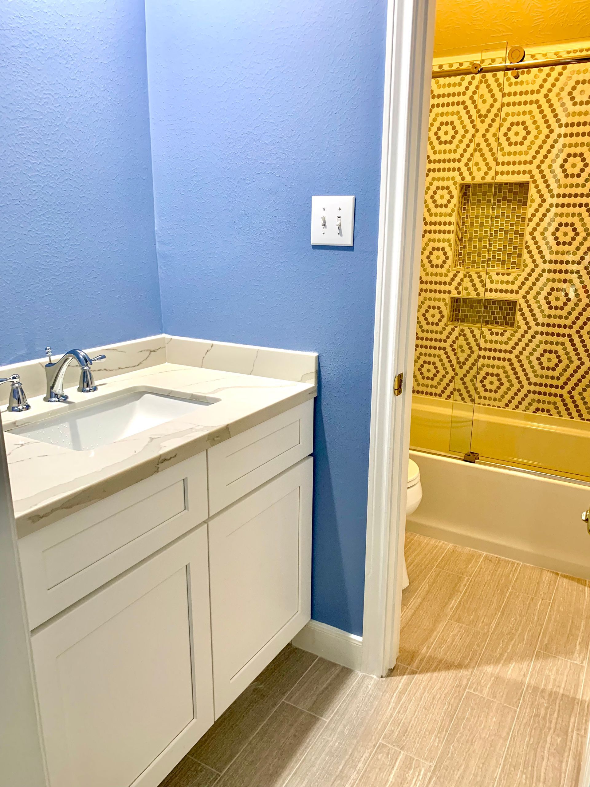 Bathroom vanity beside a shower with yellow patterned tile and a white curtain