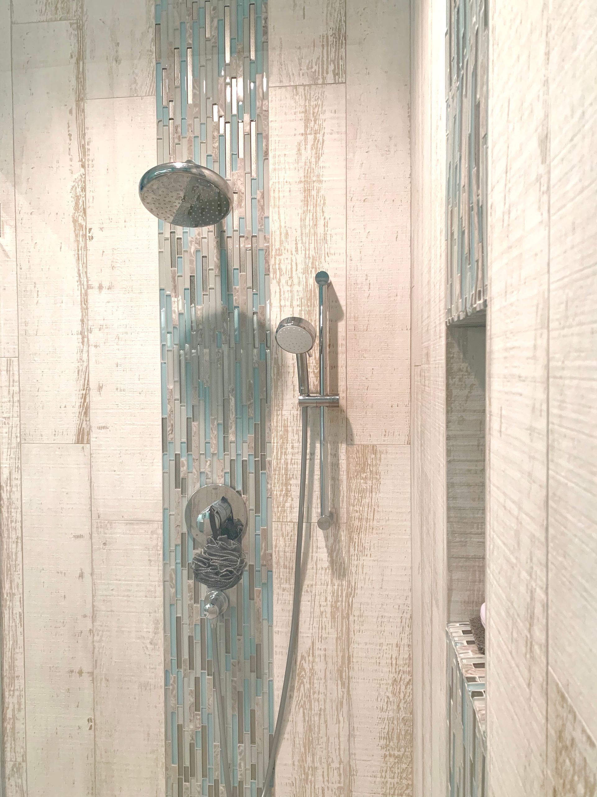 Bathroom shower with glass door, chrome fixtures, and water-streaked paneling