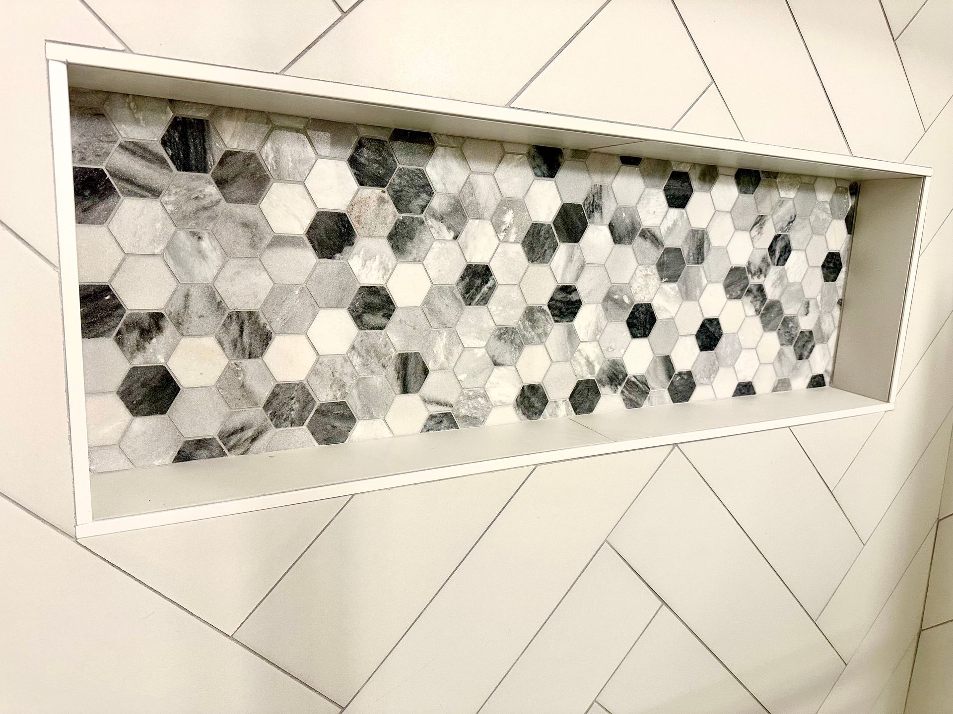 Rectangular wall niche lined with black-and-white hexagonal mosaic tiles.
