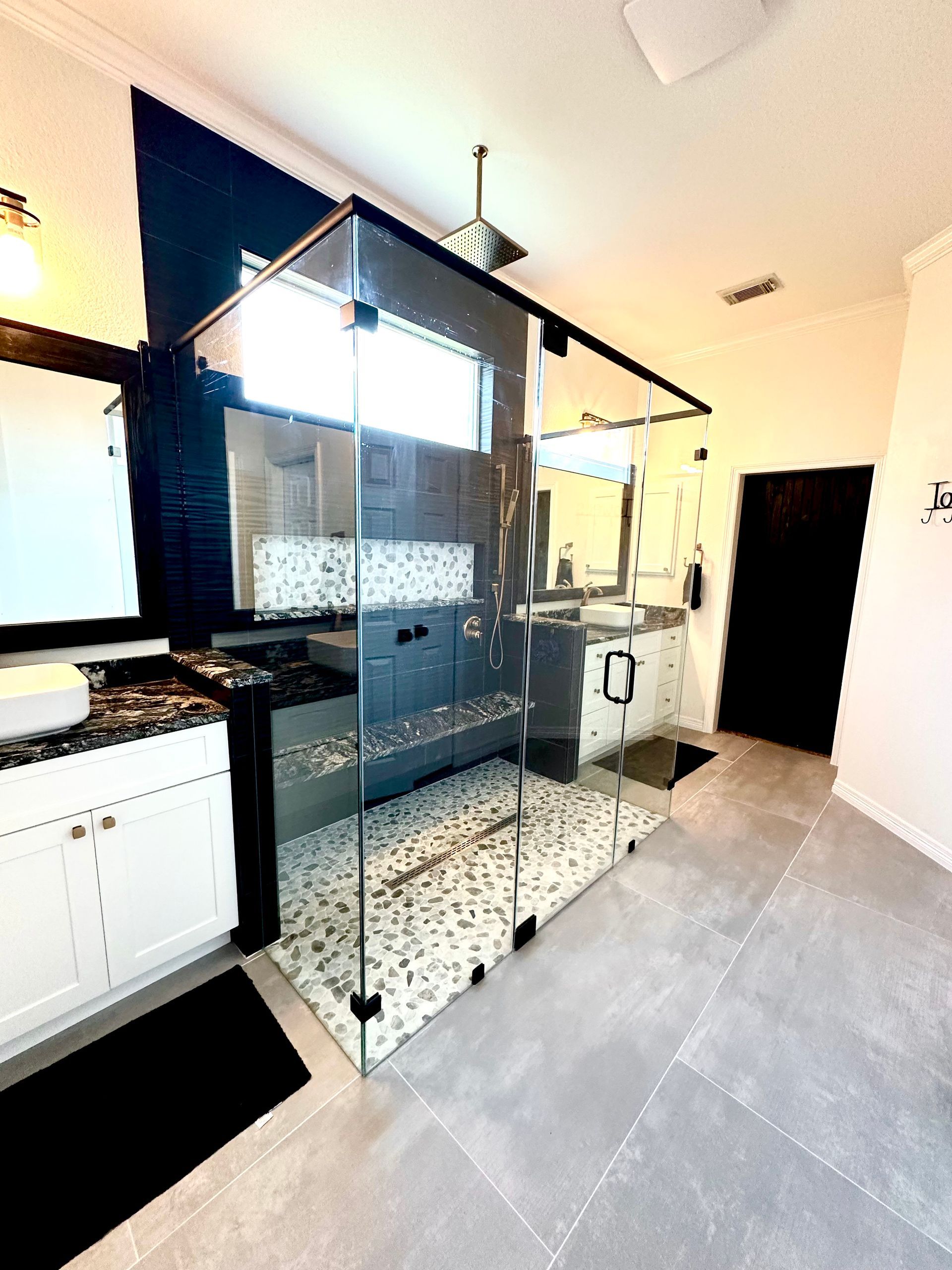 Modern kitchen with dark cabinets, white countertops, and patterned tile flooring, viewed from a doorway
