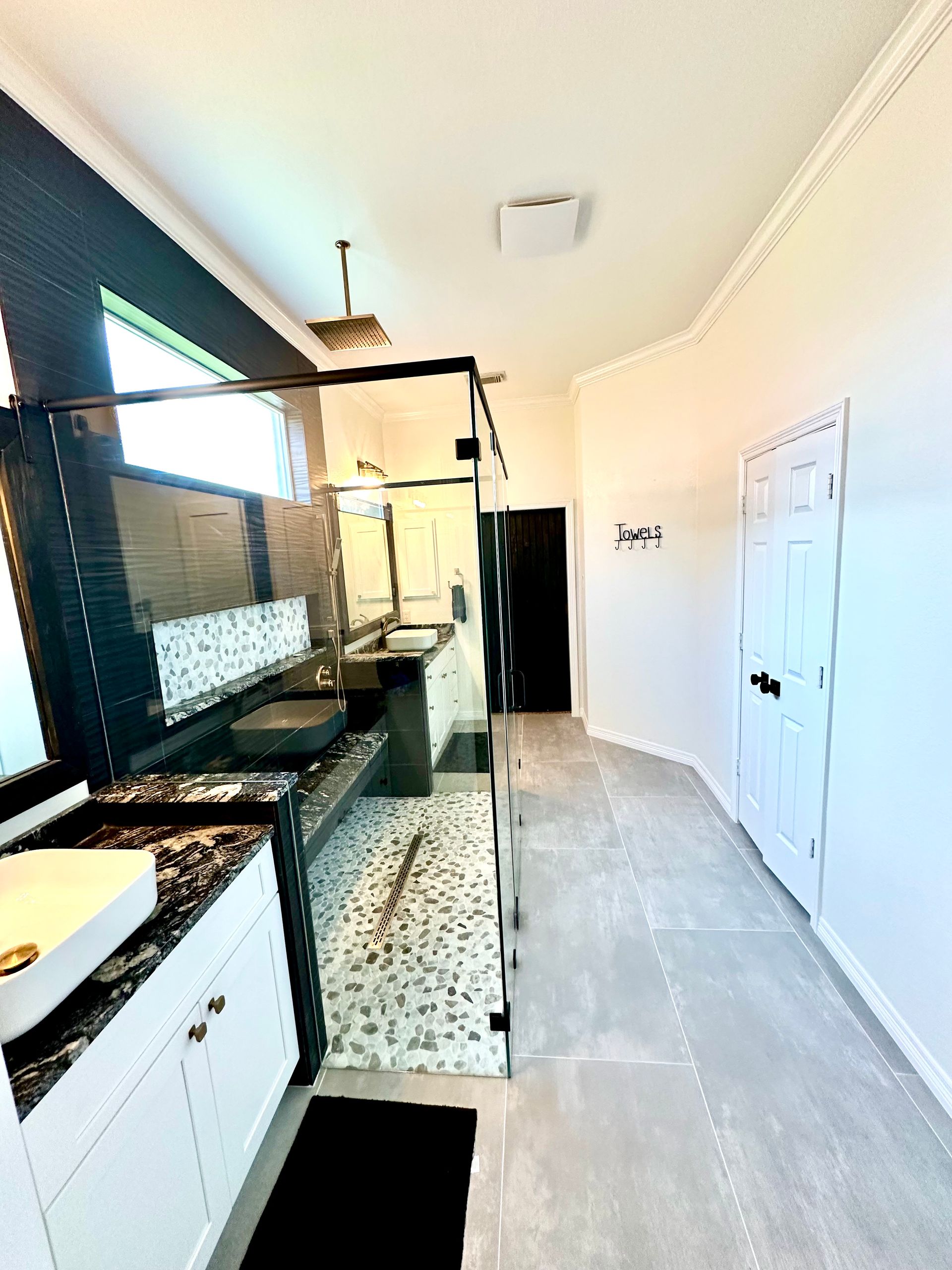 Modern kitchen with black counters, white cabinets, and a long gray-tiled floor corridor