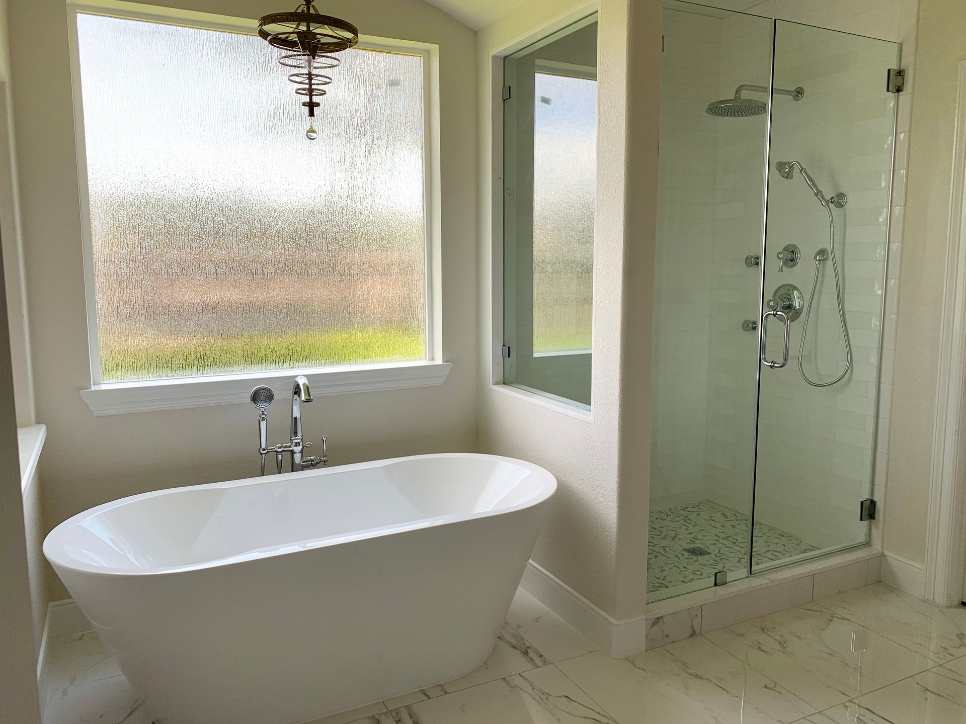 Modern white bathroom with a freestanding tub, glass shower, and frosted window above the tub