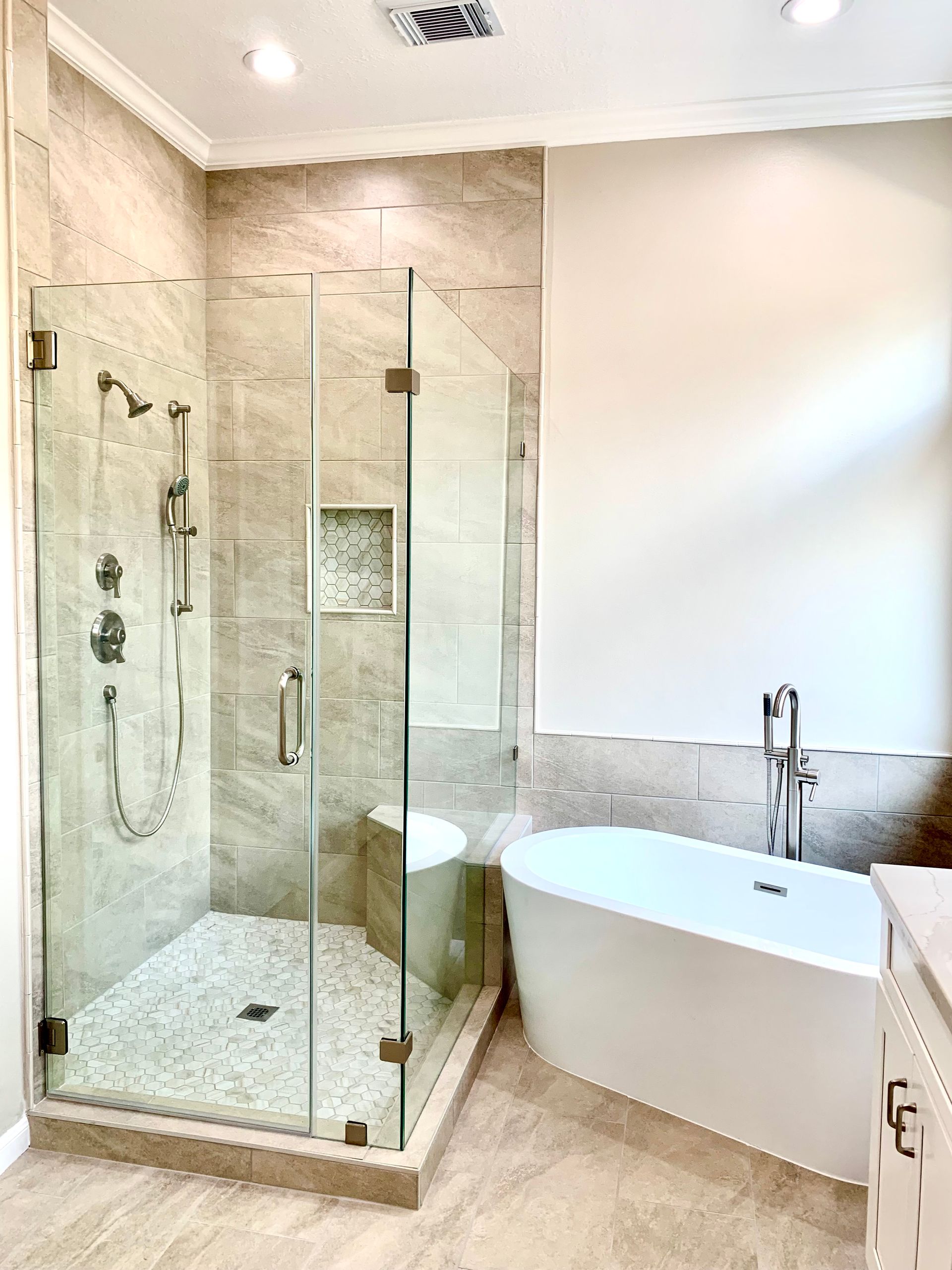 Modern bathroom with glass walk-in shower, freestanding tub, and white tile walls.