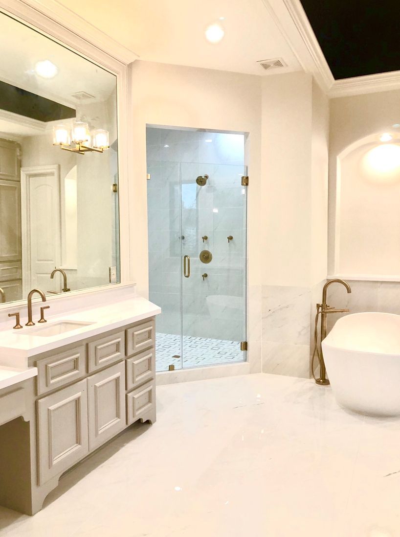 Bright white luxury bathroom with glass shower, vanity, mirror, and freestanding tub.