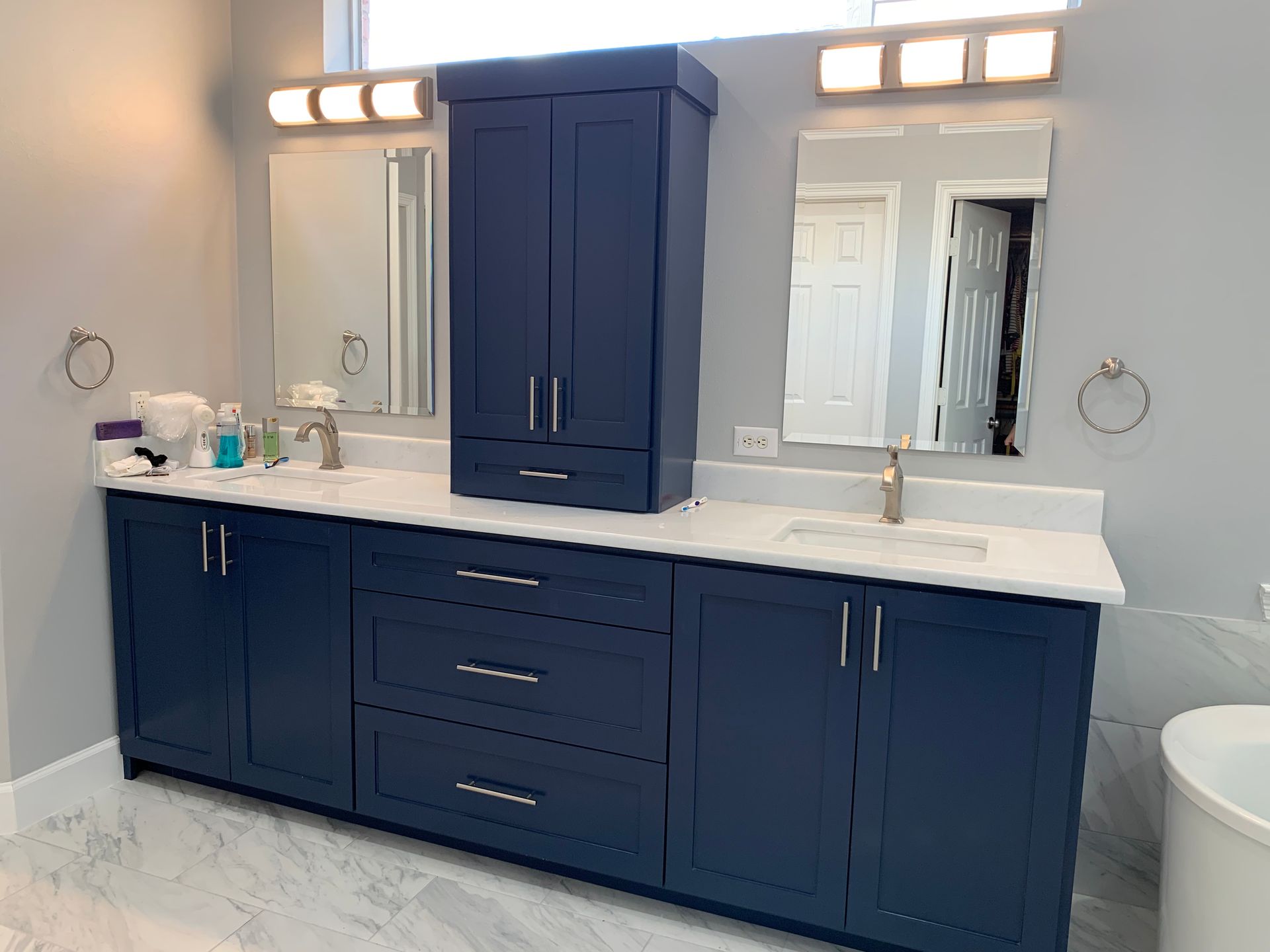 Blue bathroom vanity with double sinks, mirrors, and wall sconces above a white countertop.